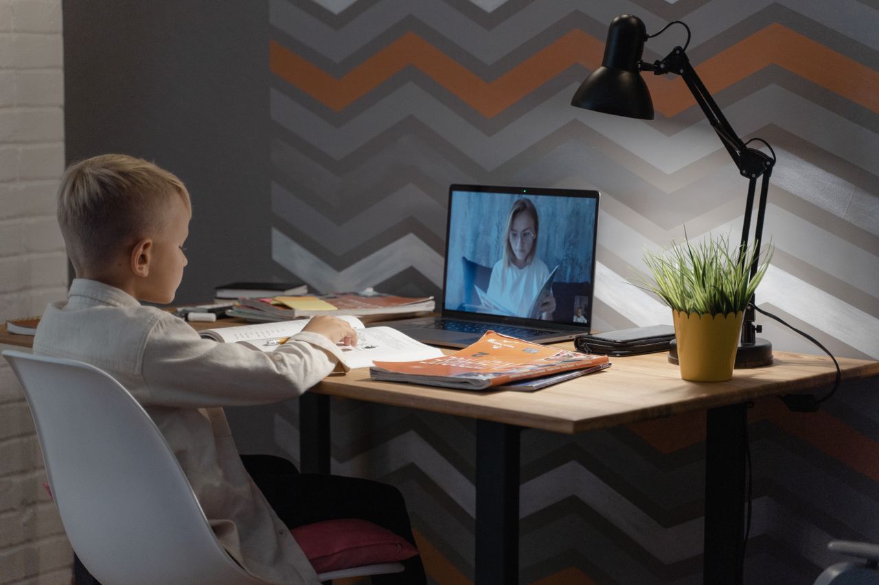 A young boy focused on a virtual class at his home desk, embracing modern education technology.
